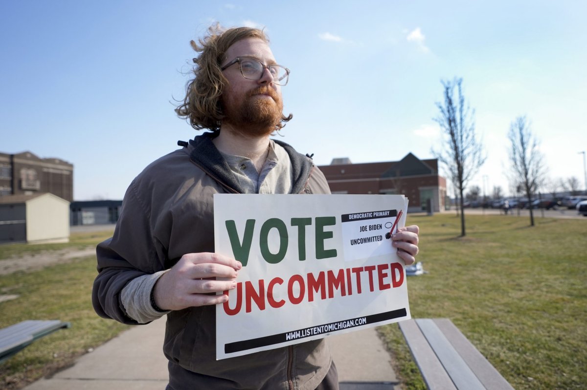 Eric Suter-Bull holds a Vote Uncommitted sign outside a voting location at Saline Intermediate School for the Michigan primary election in Dearborn, Mich., Tuesday, Feb. 27, 2024. Michigan is the last major primary state before Super Tuesday and a critical swing state in November’s general election. (AP Photo/Paul Sancya)